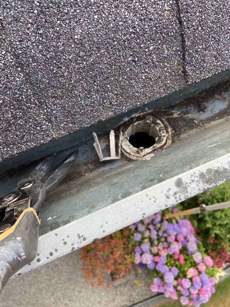 Downspout outlet being checked after gutter cleaning