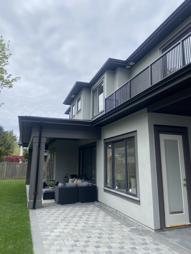 Finished residential exterior with black gutters and patio area