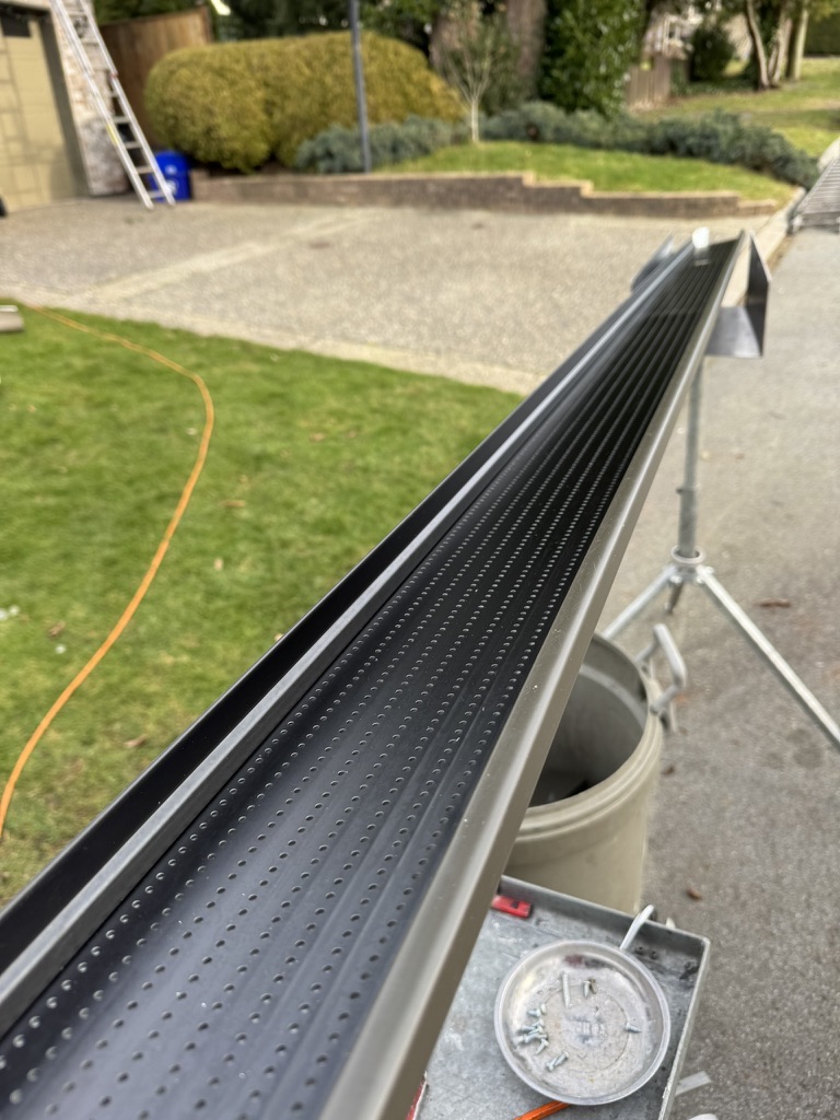 Close-up of black perforated gutter guard on a work stand