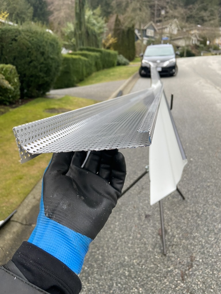 Installer holding perforated silver gutter guard profile