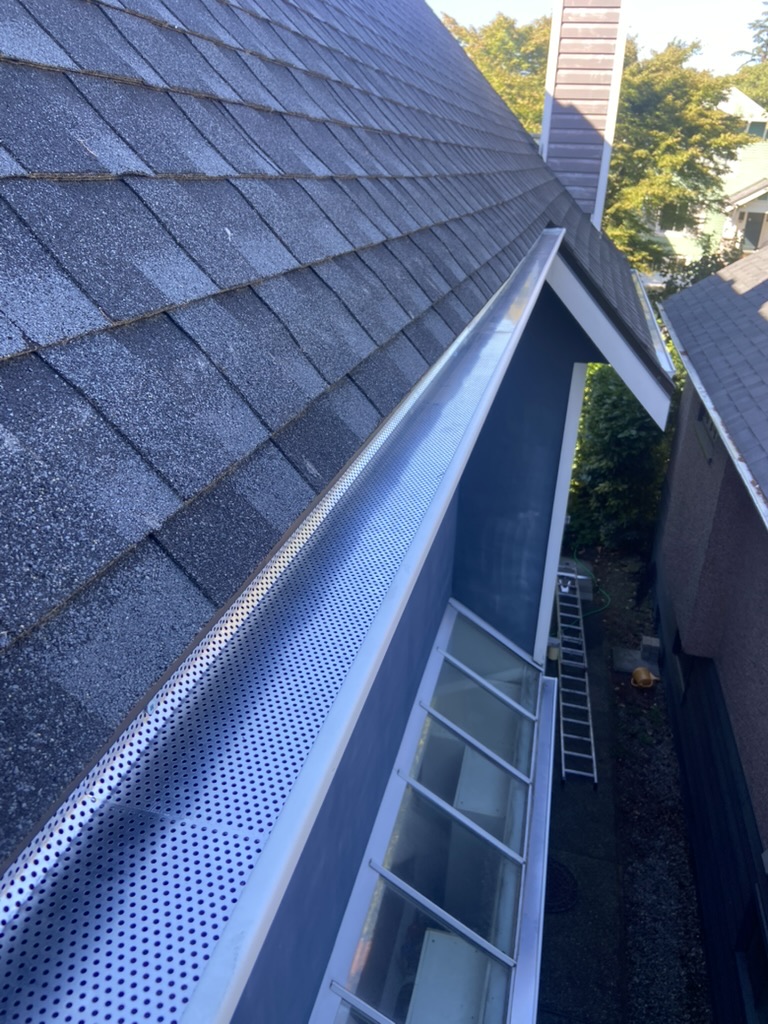 Finished gutter guard installation along a shingle roofline