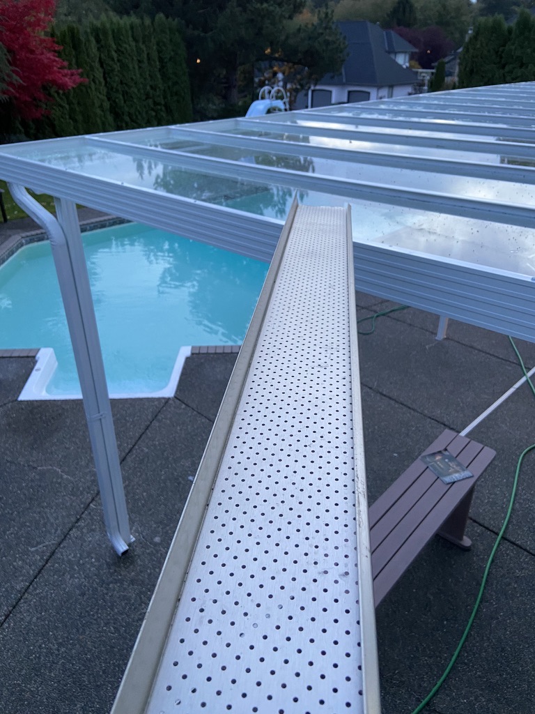 Finished white gutter guard near a patio cover and pool area