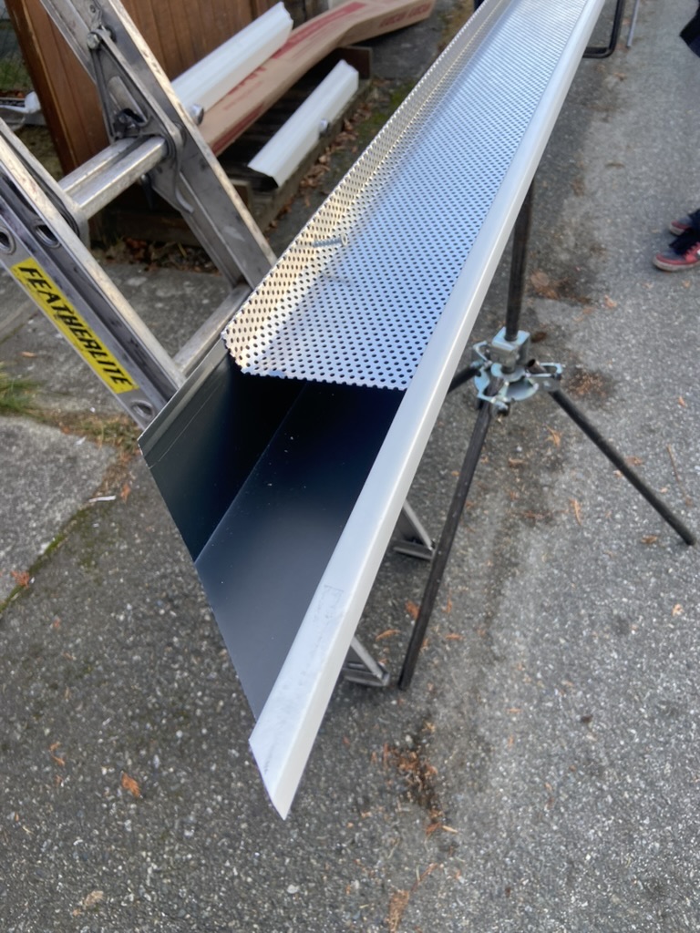 White gutter and guard material prepared beside ladder access