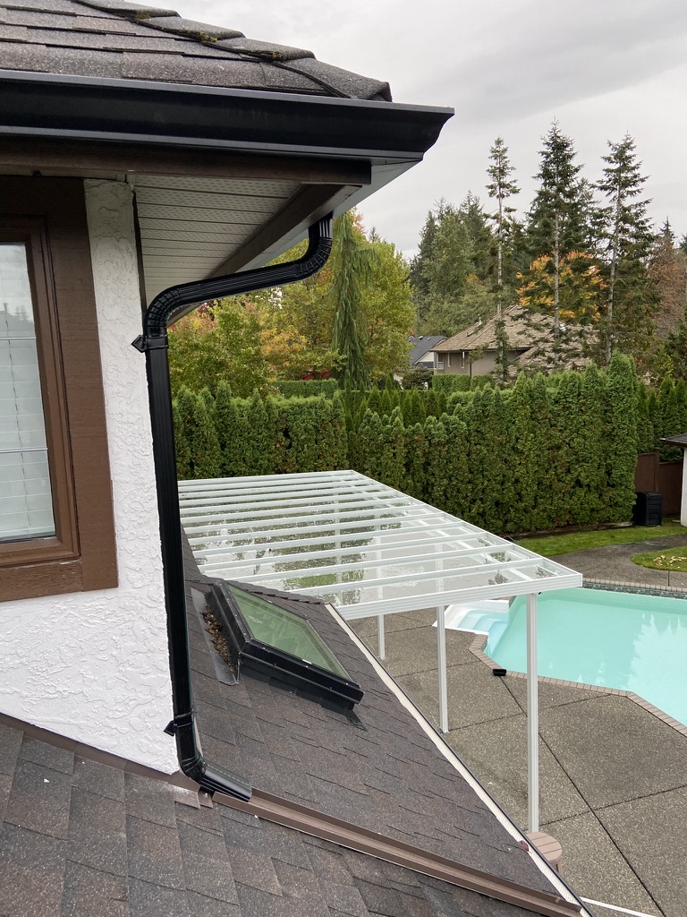 Finished black downspout beside a patio roof