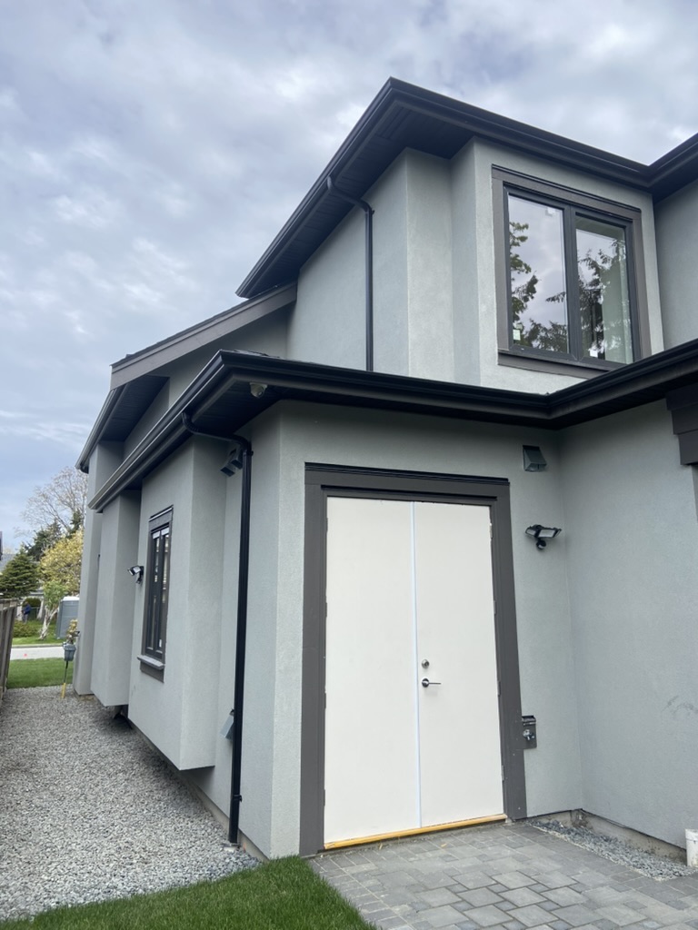 Completed black seamless gutters and downspouts on a modern home