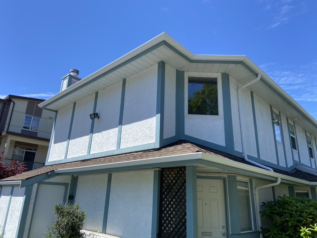 Completed white gutters and downspouts on a strata-style building