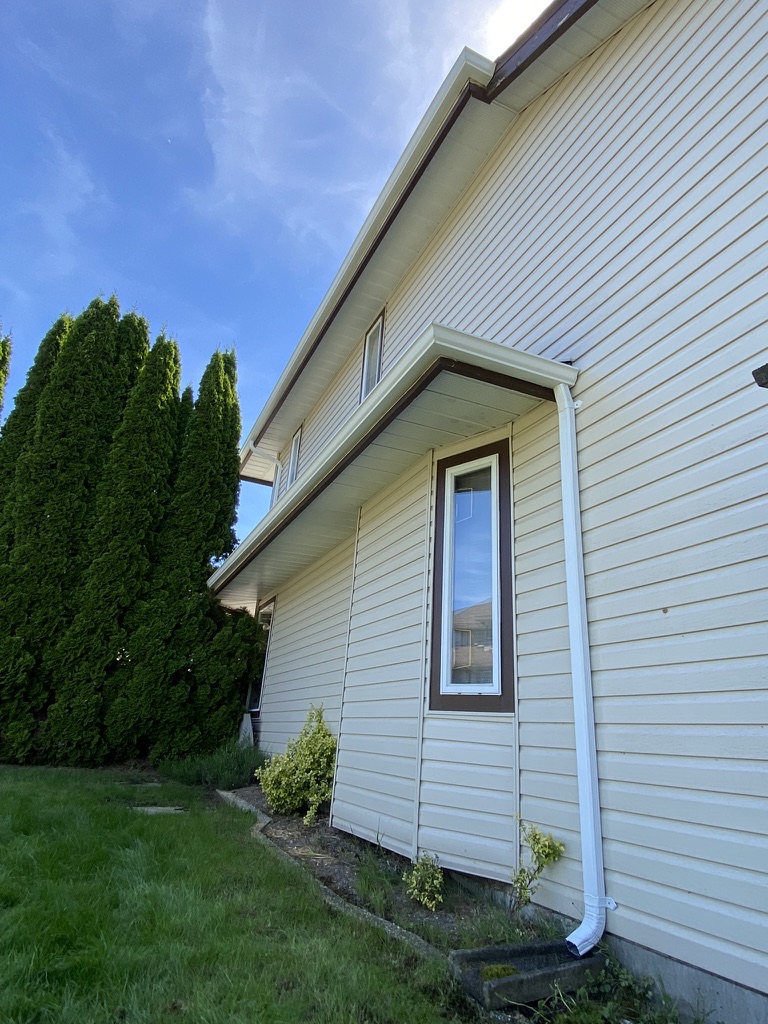 Finished white downspout on a residential side wall