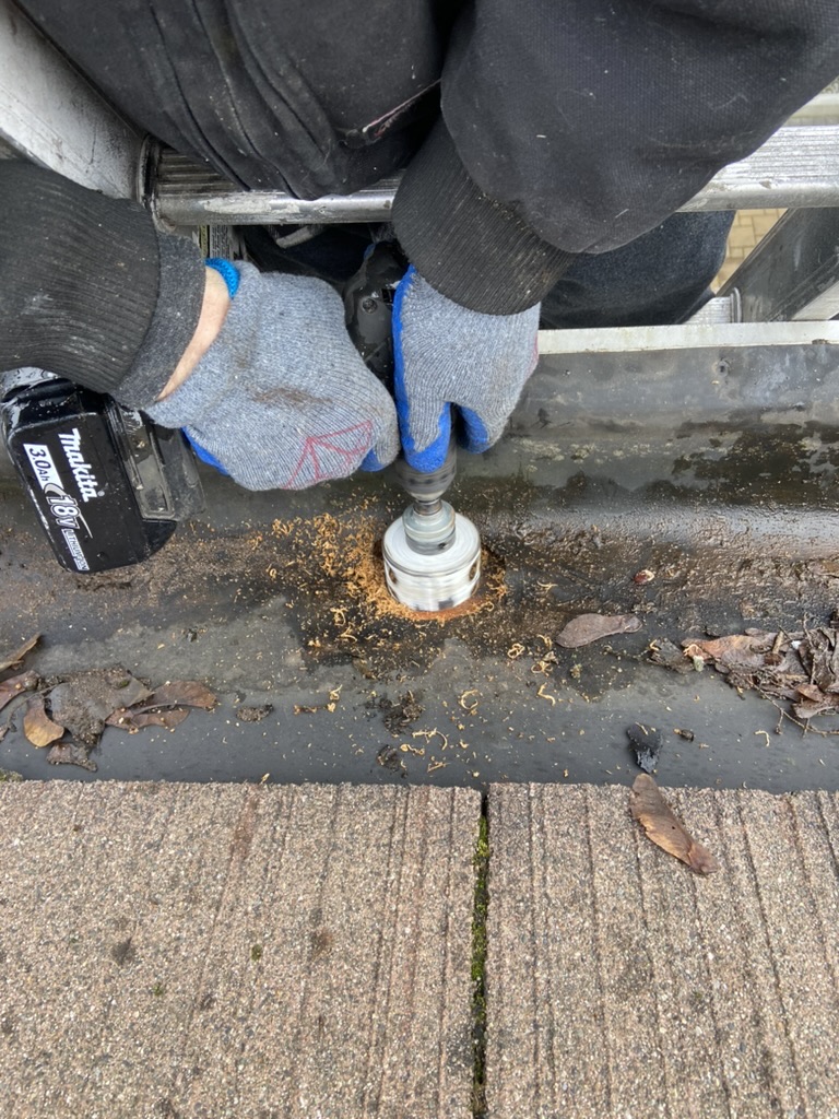 Installer cutting a new downspout outlet during gutter repair