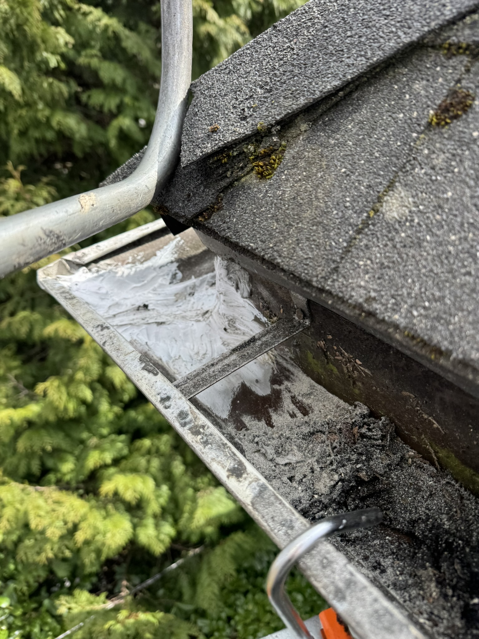 White sealant applied at roof edge gutter repair