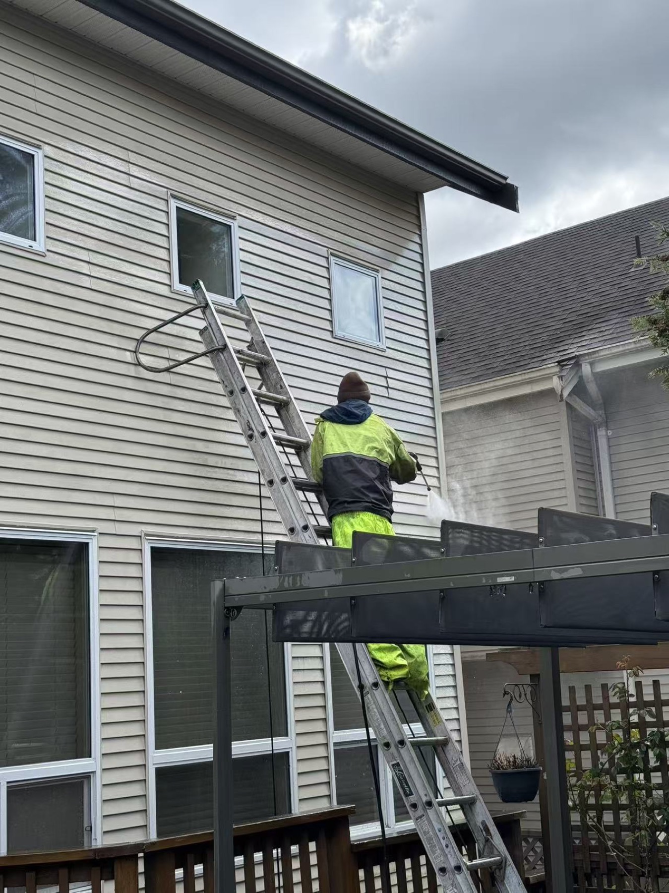 Exterior pressure washing around siding and patio structure