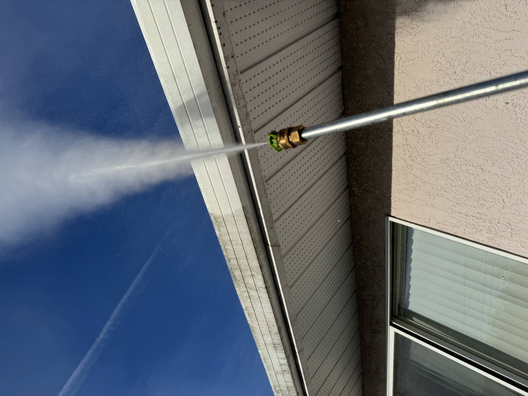 Close-up pressure washing nozzle at soffit