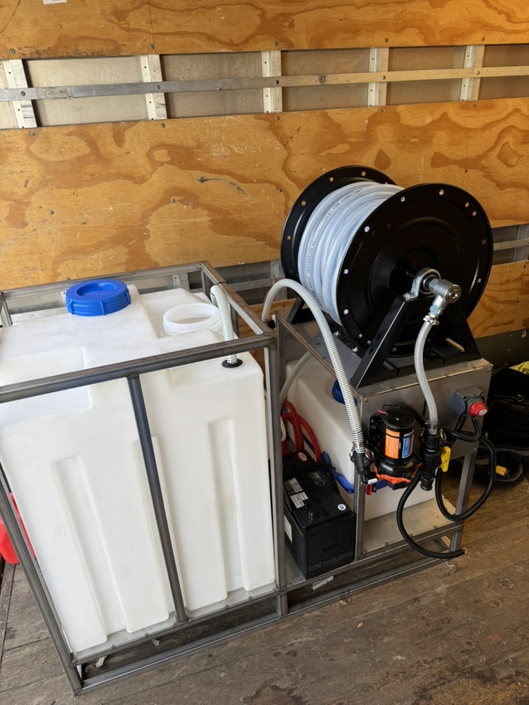 Roof treatment equipment and hose reel organized in a work trailer