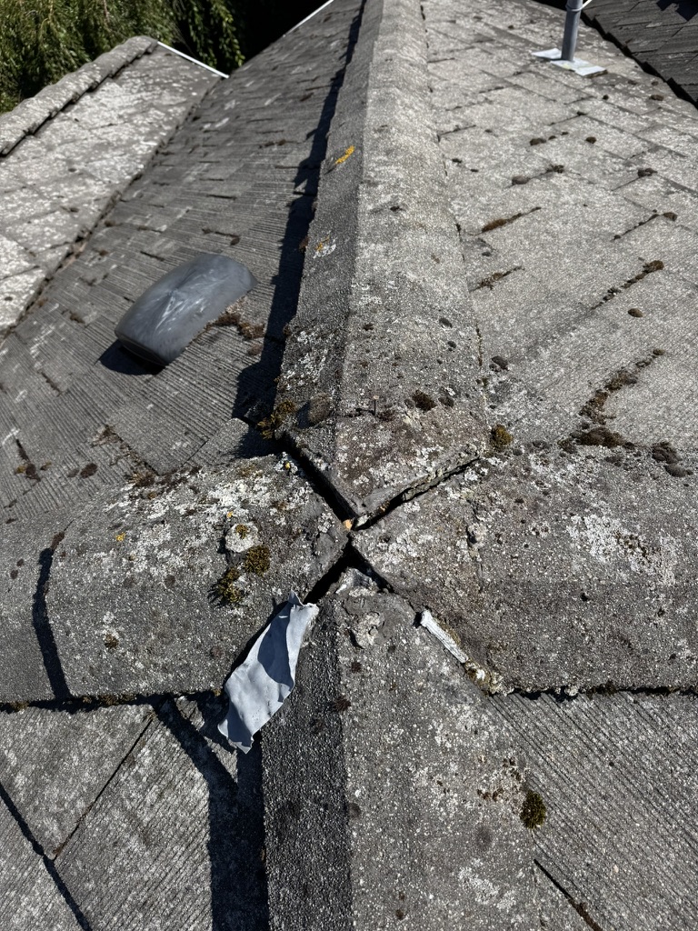 Closeup of cracked tile ridge detail during roof repair review