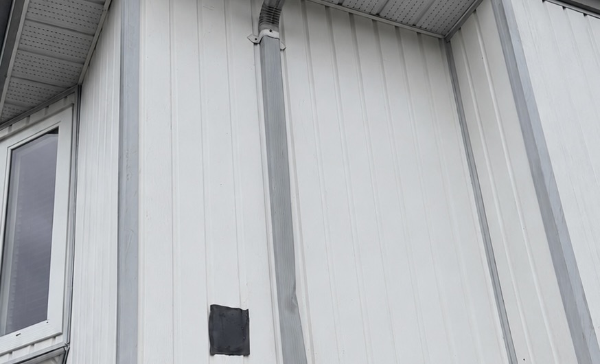 Repaired vertical metal siding panel on a residential exterior