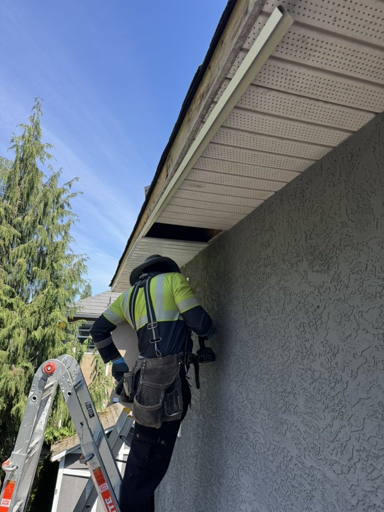 Worker installing soffit along roof eave